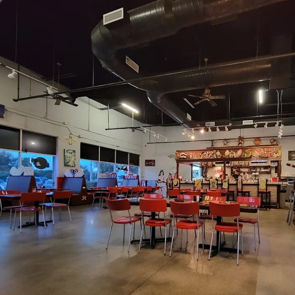 Interior of Las Palmas Restaurant with red chairs, dark tables, and a bar area with decorative carvings.