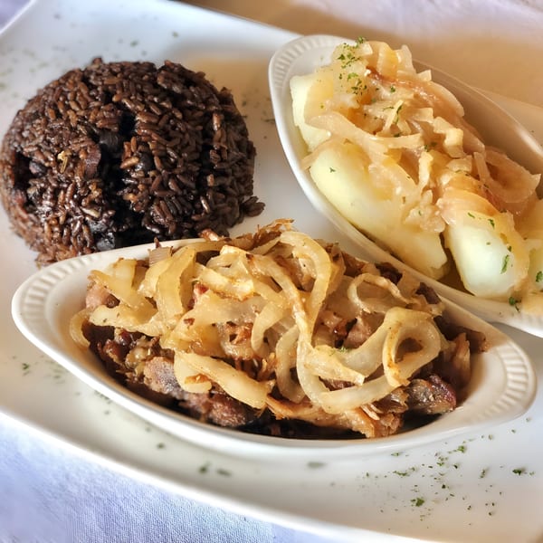 Cuban meal with black beans and rice, yuca with garlic sauce, and steak with onions.