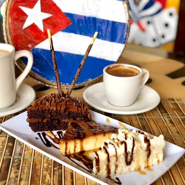 Cuban desserts: chocolate cake, flan, tres leches, and coffee, with a Cuban flag in the background.