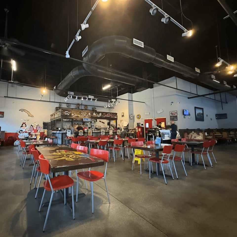 Spacious interior of Las Palmas Restaurant with red chairs, dark tables, and a bar area.