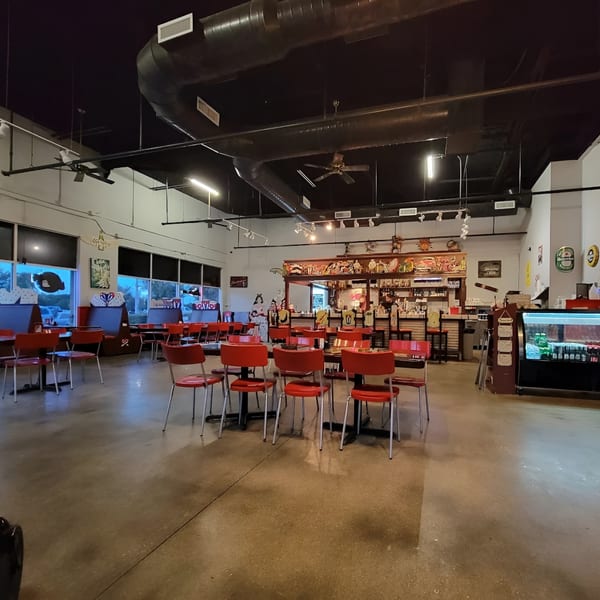 Interior of Las Palmas Restaurant with red chairs, dark tables, and a bar area with Cuban decor.