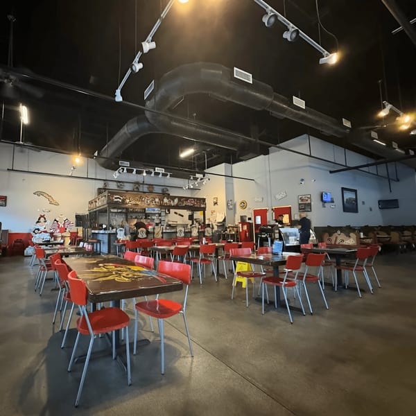 Spacious interior of Las Palmas Restaurant with red chairs, dark tables, and a bar area.